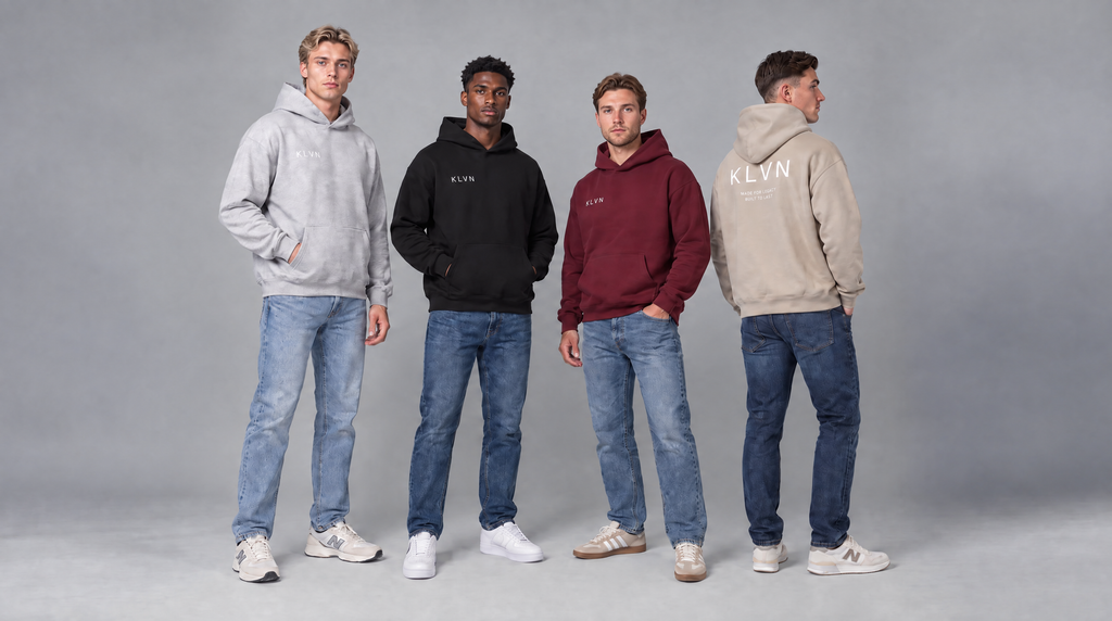 Four men modeling Klyn brand hoodies in different colors (gray, black, maroon, and beige) paired with blue jeans, standing against a neutral gray studio background.